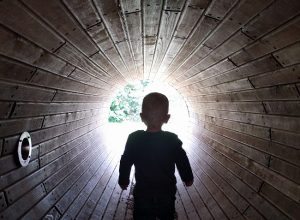 Max in dark tunnel with light coming through at the end