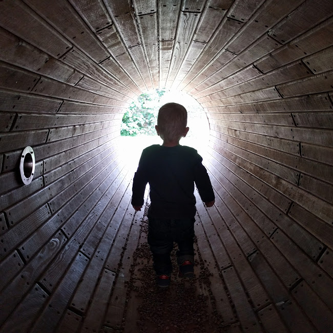 Max in dark tunnel with light coming through at the end