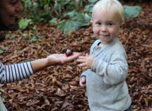 Conker held out on hand to toddler, toddler with big grin on his face