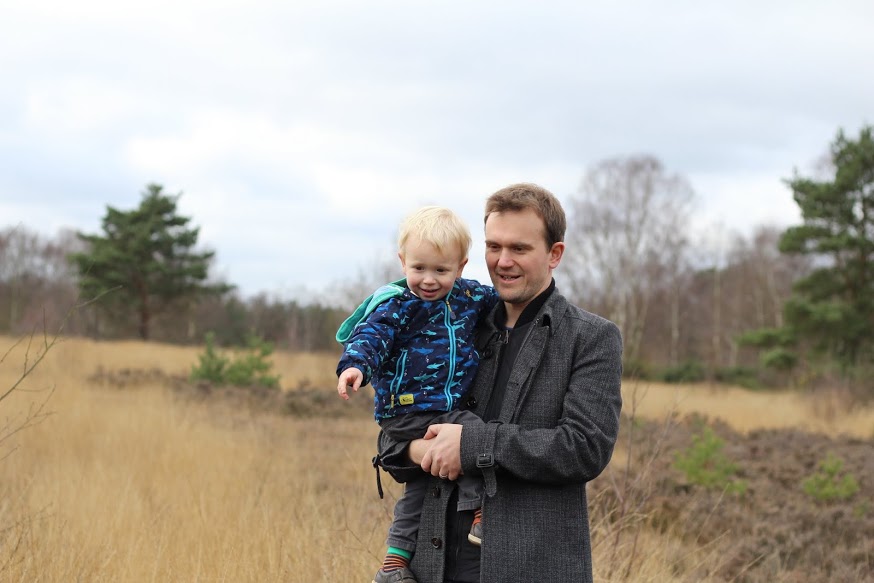 Daddy holding Max, Max pointing down to mud on the ground