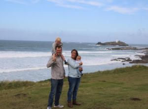 Katy holding Ben, John with Max on shoulders, on cliffs with Godrevy lighthouse in the distance