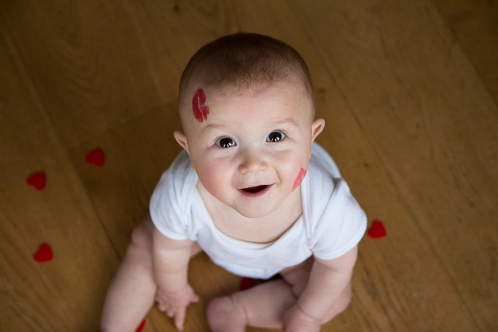 8 month old baby, sitting and looking up at the camera, smiling