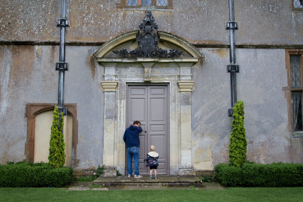 Large grey door with ornamental doorway. A man and little boy are stood in front of it.