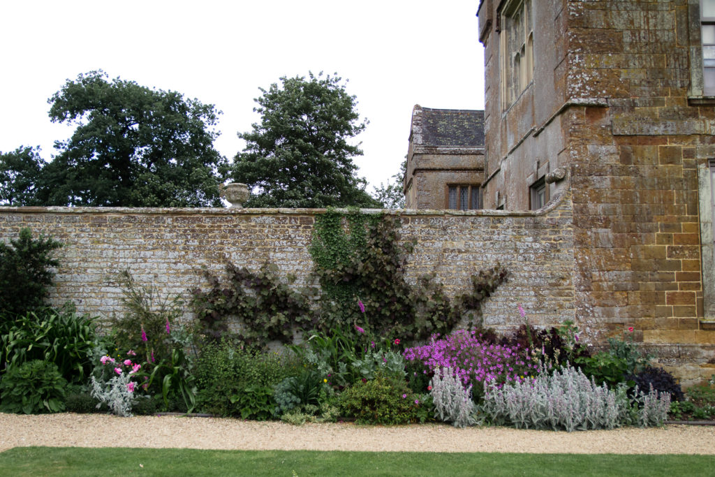 Border at Canons Ashby, planted against brick wall next to the house
